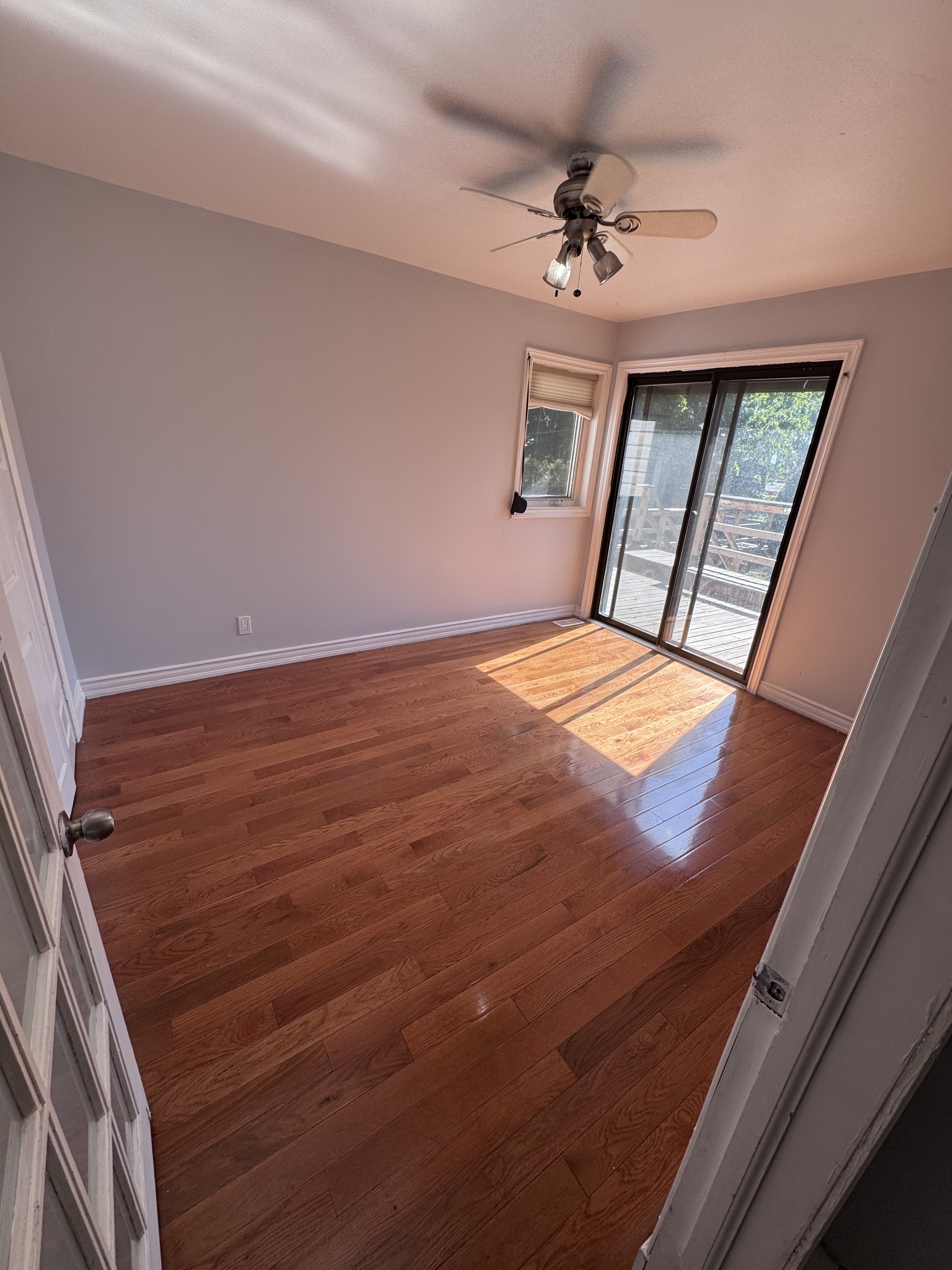 Bright main-level bedroom with hardwood floors and sliding doors to the deck