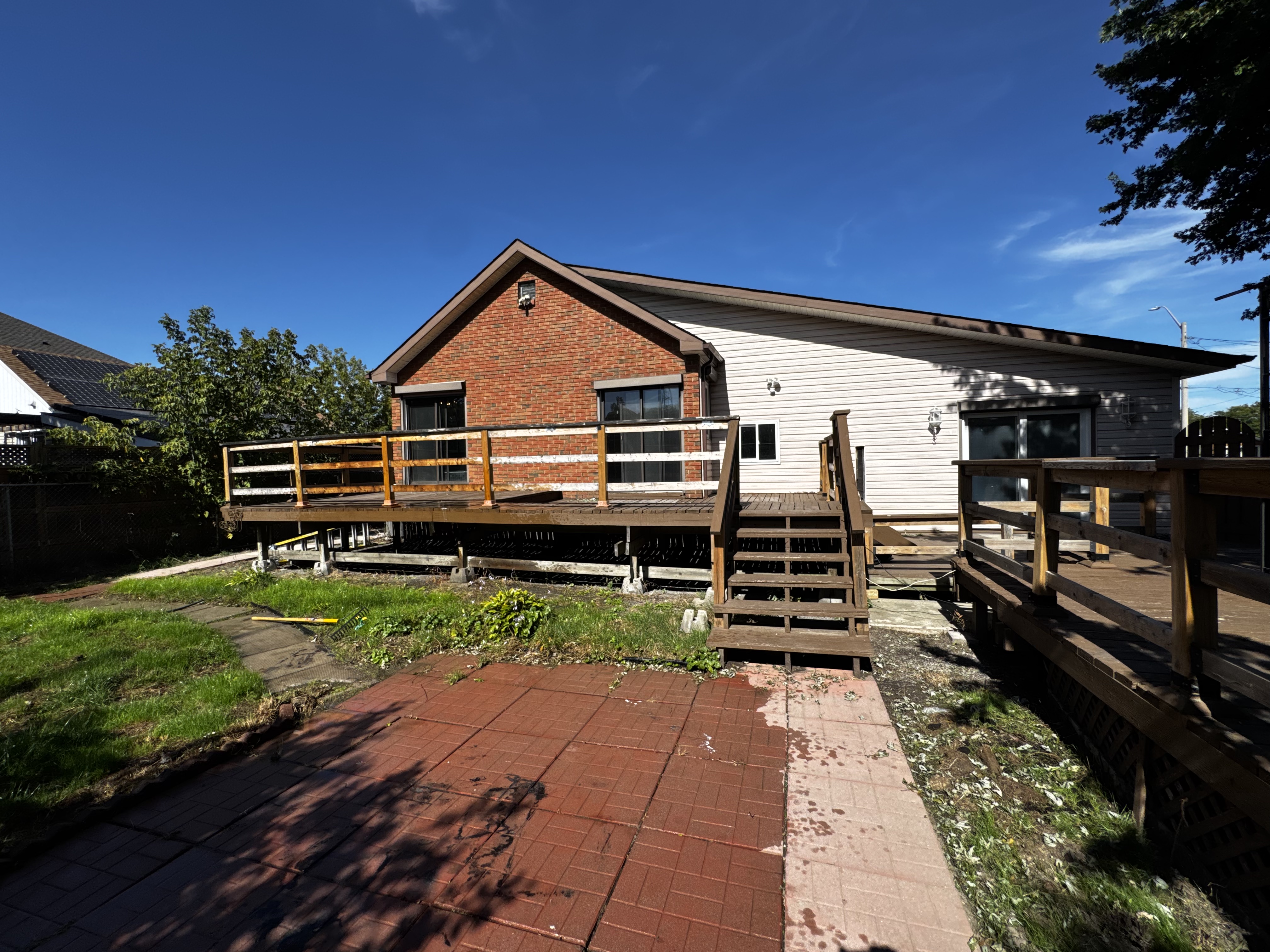 Large back deck overlooking the landscaped yard with mature trees